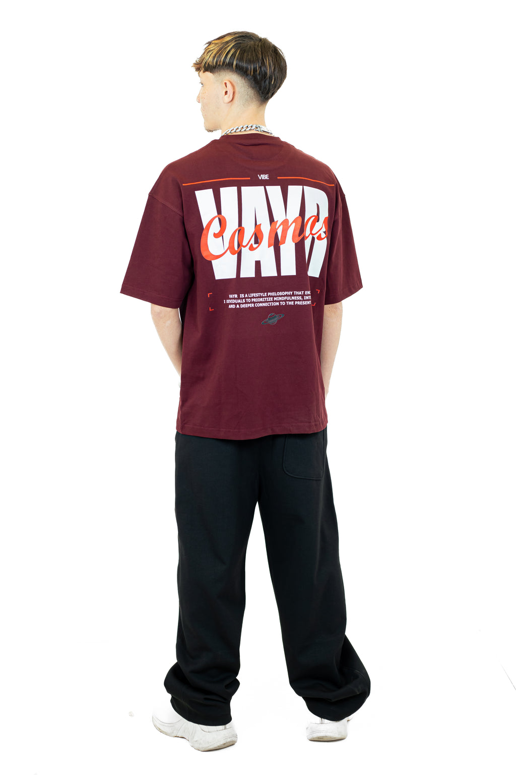 Person wearing a maroon t-shirt with text on the back, standing against a white background
