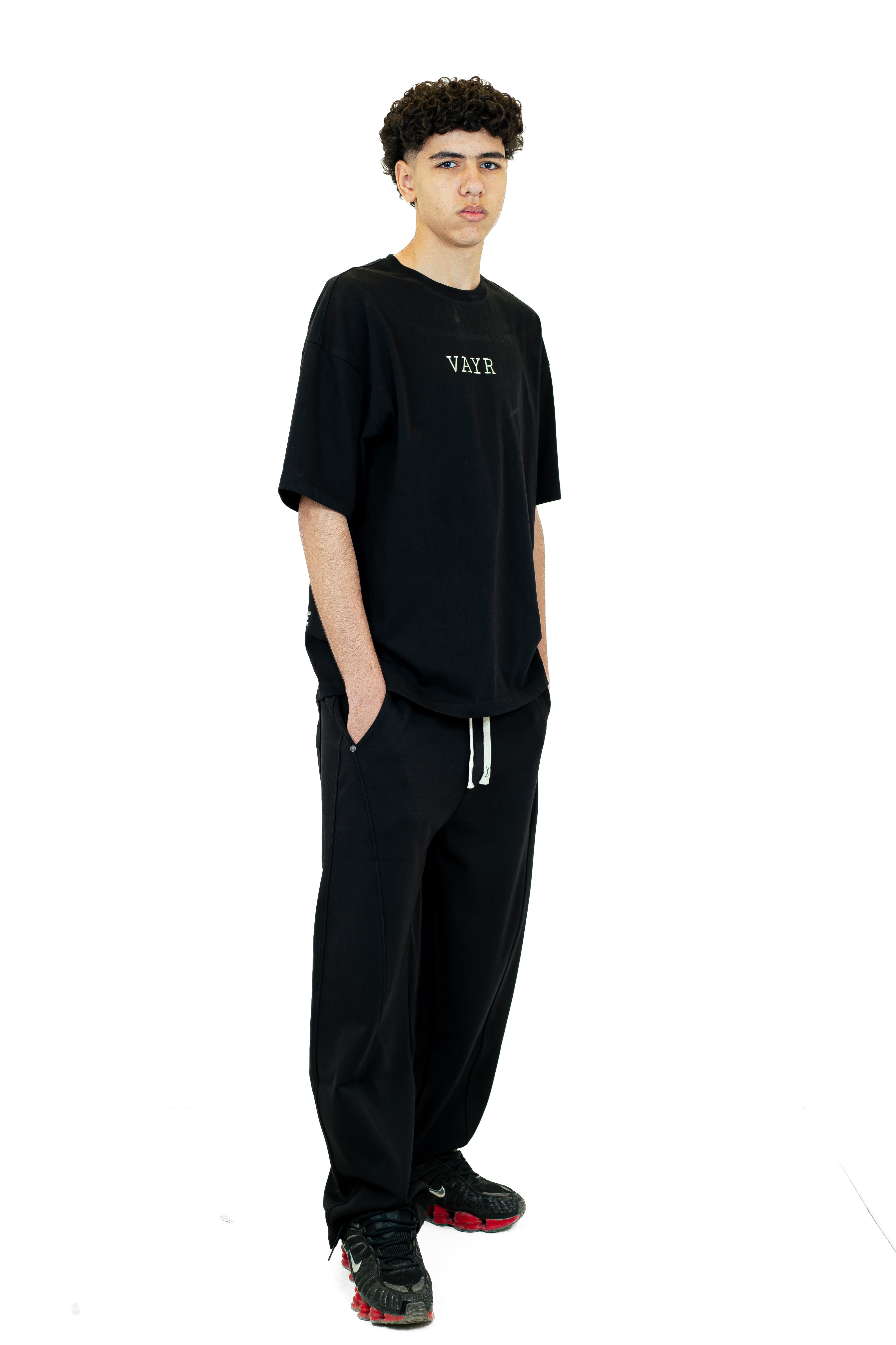 Person wearing a black t-shirt and pants on a white background